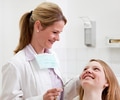 Female dentist in blue scrubs showing x-rays to patient, smiling young man.