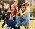 Parents with two kids smiling outdoors