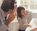 Father teaching daughter how to brush teeth in a bathroom