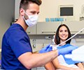 A male dentist preparing to work on a female patient