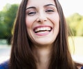 A young woman is laughing outdoors