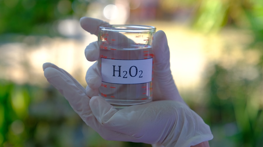 Clear hydrogen peroxide solution in a laboratory beaker, commonly used for teeth whitening and oral care.