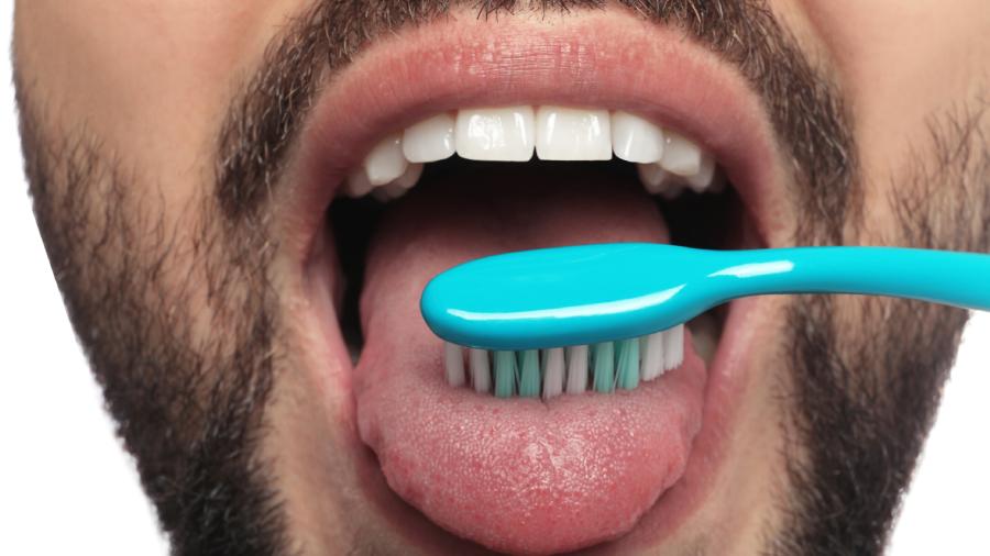 Man cleaning his tongue with a toothbrush