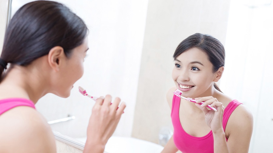 Woman brushing teeth showing how to whiten teeth