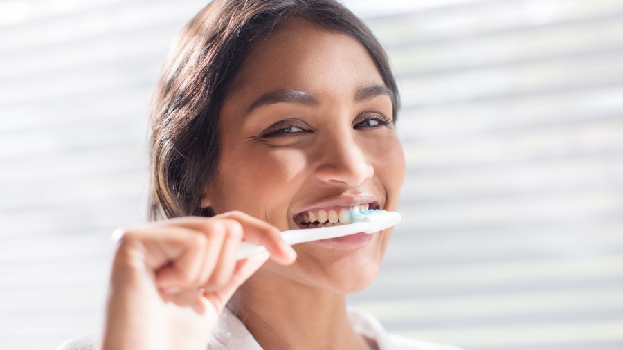 Woman brushing her teeth with mint toothpaste for better oral health