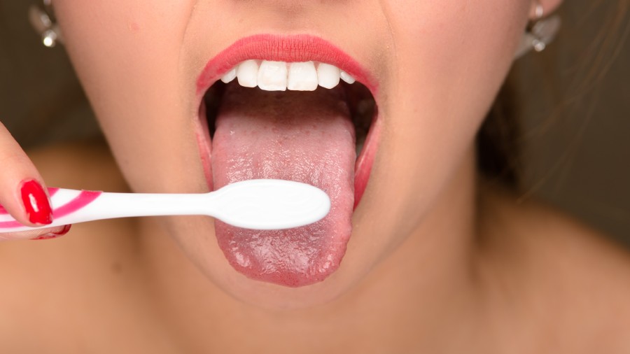 A lady using toothbrush for tongue cleaning