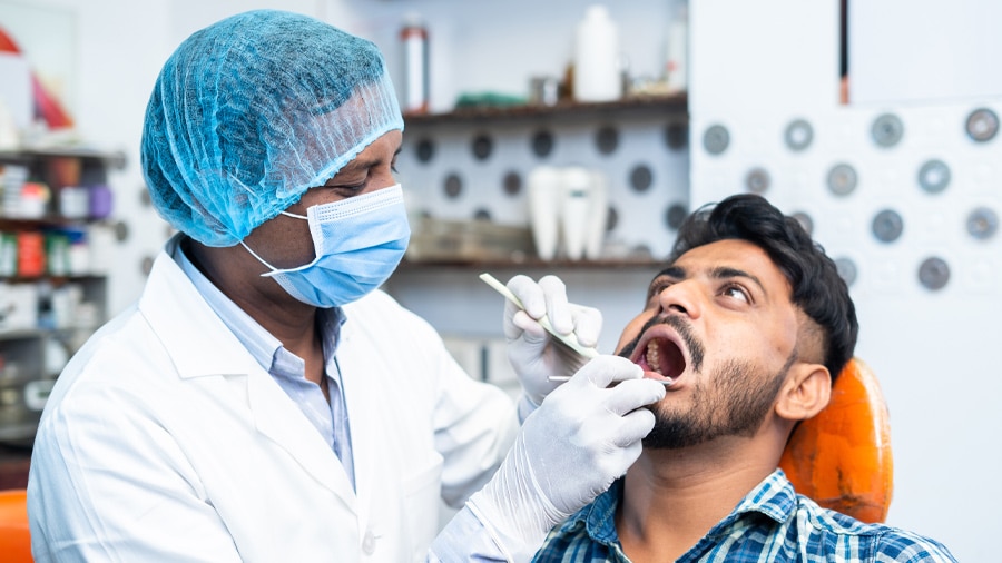 A dentist performing bleeding gums treatment for a young man.