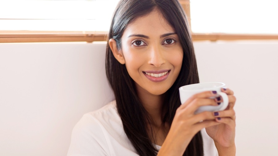 Girl smiling and holding a cup after tooth whitening
