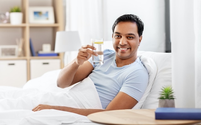 Man holding a glass of water, addressing dry mouth caused by dehydration
