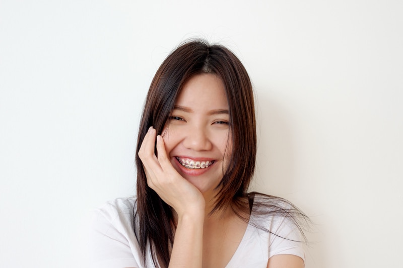 A woman smiling and touching her face