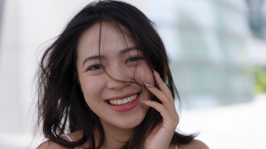 A woman smiling and touching her face