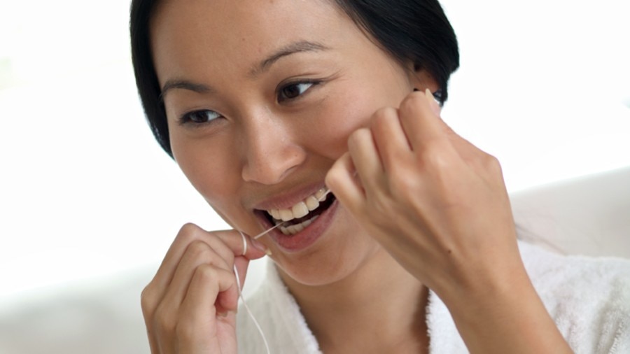Lady flossing as a treatment for bleeding gums, promoting healthy oral hygiene
