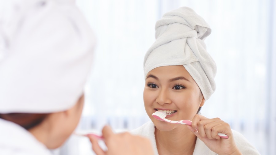 a mother and a daughter brushing their teeth with Colgate tootbrush
