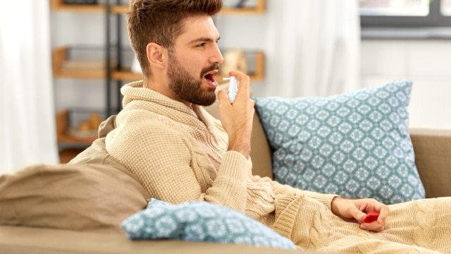 Hombre joven usando spray bucal