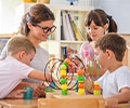 a female teacher smiling at three children playing