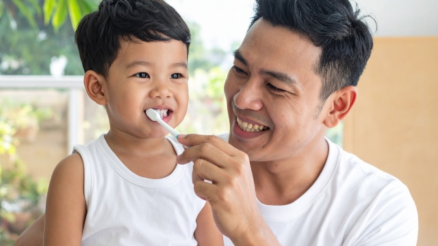 kid and dad brushing tooth
