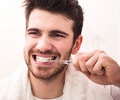 Young man brushing his teeth while looking into a mirror
