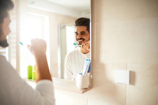 Man brushing teeth with fluoride toothpaste for strong enamel protection