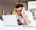 Man in glasses and white shirt researching on laptop computer