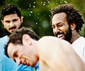 man smiling in a white tshirt enjoying himself outside with his freinds