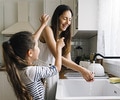 Mother and daughter washing dishes and having fun together