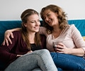 Mother and teen daughter sitting in a sofa at home