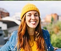 portrait of smiling young woman wearing yellow cap sticking out tongue