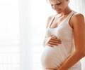Pregnant woman smiling holding her belly