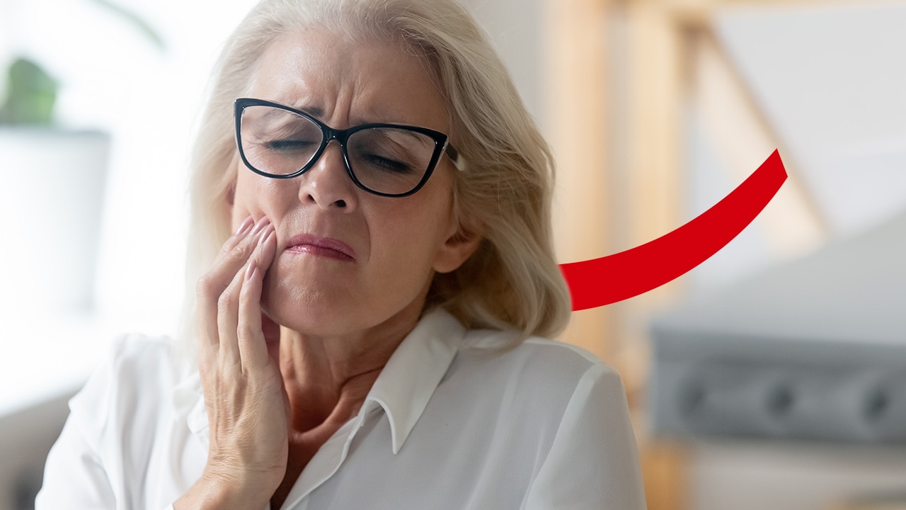 Senior woman holding her cheek in pain 