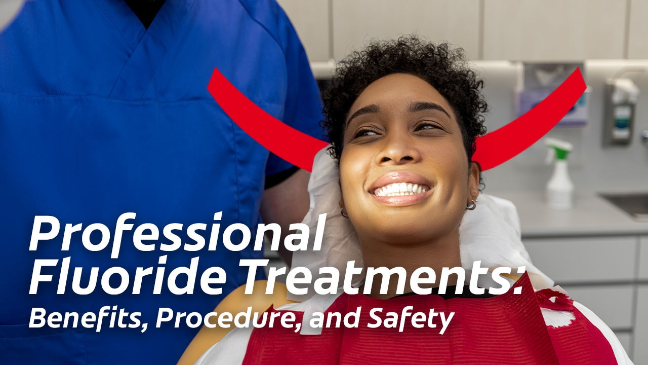 Woman smiling in a dental chair during an appointment, with a healthcare professional standing next to her. Overlay text reads: Professional Fluoride Treatments: Benefits, Procedure, and Safety.