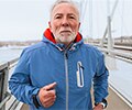 A senior man in a blue coat is running on the bridge