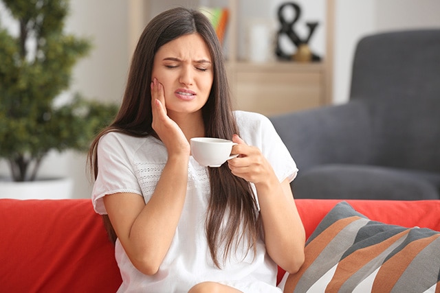 Mujer tomando un café con dolor en la boca
