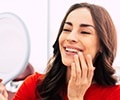 A woman is looking at her teeth in the mirror