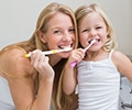 Mother and daughter brushing their teeth
