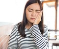 A young woman is having a toothache indoors