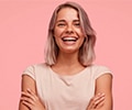 woman with braces smiling brightly with her arm crossed