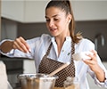 Woman with apron on is baking in a kitchen