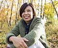 smiling woman sitting in the woods