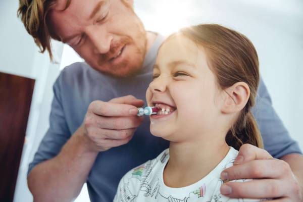 Padre enseñándole a su hija a lavarse los dientes