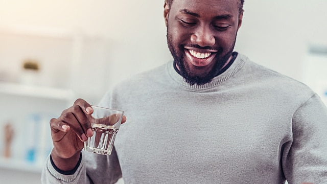 Hombre con blanca sonrisa tomando agua