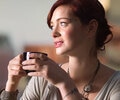 A woman is drinking coffee in a cafe