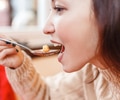 Profile of a young woman eating a bowl of soup