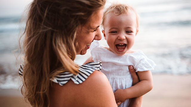 Madre y su bebé sonriendo en la playa