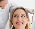 Female Dentist at work on a smiling woman patient in office.