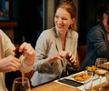 A man and woman sitting at a bar and talking and laughing while eating