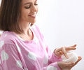 Young woman holding a jar of natural coconut oil in bathroom