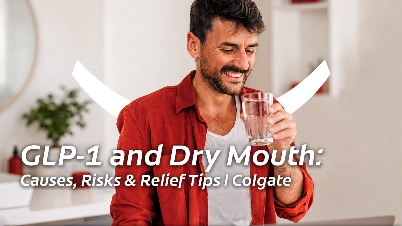 A smiling, dark-haired man in a white vest and red shirt, holding a glass of water up to his mouth to relieve GLP-1 dry mouth. 