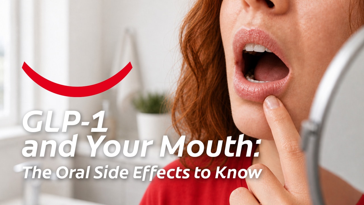 A red-haired woman standing with her mouth open in front of a mirror and examining her lips and mouth for signs of GLP-1 oral side effects. 