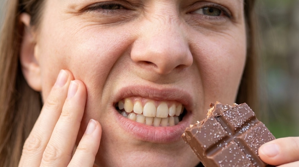 Dientes sensibles al azúcar: persona con dolor al comer chocolate
