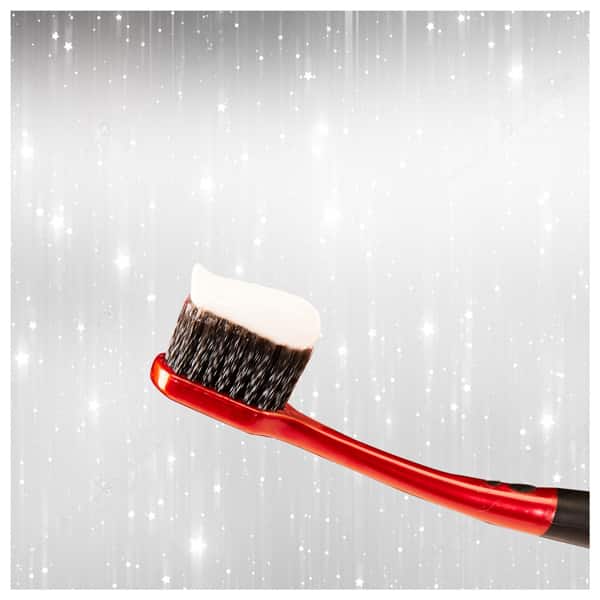 red color brush with whitening toothpaste on the black bristles